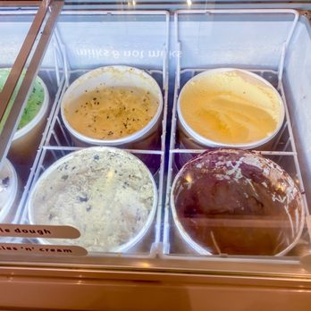 Insomnia Cookies - Ice cream! - A selection of ice cream flavors is visible inside a freezer at Insomnia Cookies in Des Moines, IA. The tubs include cookie dough, cookies 'n' cream, and other flavors, with some labels visible on the freezer glass. The image captures the variety of ice cream options available at the store. - Bakeries Near Me - Des Moines, Iowa