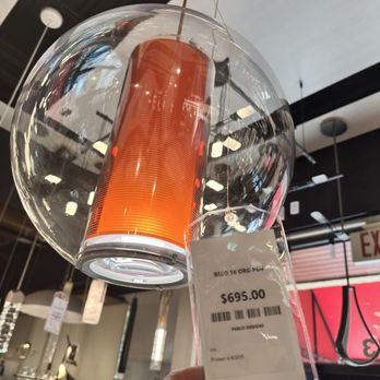 LBU Lighting - A pendant light with a cylindrical orange component inside a transparent glass globe, hanging from the ceiling of a lighting store. - Lighting Stores Near Me - Boca Raton, Florida
