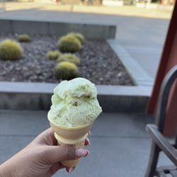 Single scoop pistachio ice cream on a plain cone