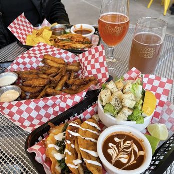 Claim 52 Kitchen - A meal with tacos, fries, salad, and beverages including beer and soda on a metal table at Claim 52 Kitchen in Eugene, OR. - Gastropubs Near Me - Eugene, Oregon