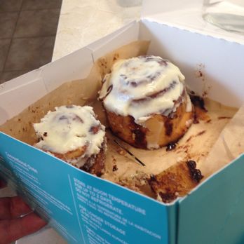 Cinnabon - a hand holding a box of cinnamon buns - Bakeries Near Me - Houston, Texas