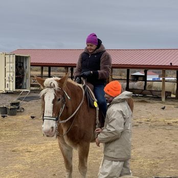 12 Mile Stables - My sister aboard her horse with Dustin adjusting the stirrups. - Horseback Riding Near Me - Aurora, Colorado