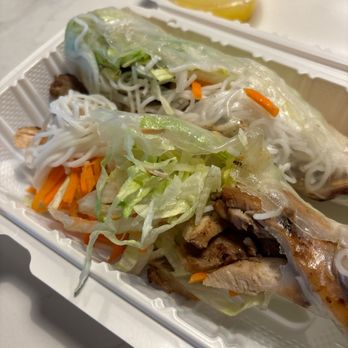 Pho Town - The spring rolls arrived busted open and included shrimp (which we didn't order) - when we called politely they hung up on us. - Two Vietnamese spring rolls filled with vegetables and meat are placed in a white takeout container, accompanied by a small cup of yellow dipping sauce. - Vietnamese Near Me - Prince Frederick, Maryland