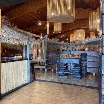 Hot Rocks - It's a vibe - The image shows the interior of Hot Rocks restaurant featuring tropical-themed decor, wooden ceiling, and hanging wooden light fixtures. - New American Near Me - Wisconsin Dells, Wisconsin