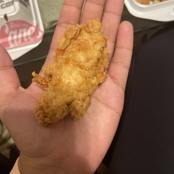 Raising Cane's Chicken Fingers - a hand holding a piece of fried chicken - Fast Food Near Me - Benbrook, Texas Raising Cane's Chicken Fingers - a hand holding a piece of fried chicken - Fast Food Near Me - Benbrook, Texas