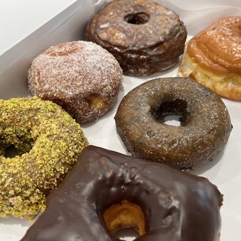 The Donuttery - Top left to right: Pistachio (vegan), vanilla cream malisada (vegan), Croissant Donut Chocolate dip, Blueberry Cake, Glazed Raised Donut - Donuts Near Me - Huntington Beach, California The Donuttery - Top left to right: Pistachio (vegan), vanilla cream malisada (vegan), Croissant Donut Chocolate dip, Blueberry Cake, Glazed Raised Donut - Donuts Near Me - Huntington Beach, California