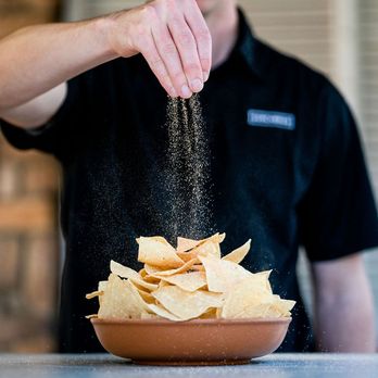 Surcheros - Douglas - a man sprinkling salt onto a bowl of nachos - Tex-Mex Near Me - Douglas, Georgia