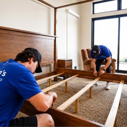 Big Ben's Moving and Storage - Two Big Ben's Moving & Storage professionals carefully assembling a wooden bed frame inside a residential home during a move.