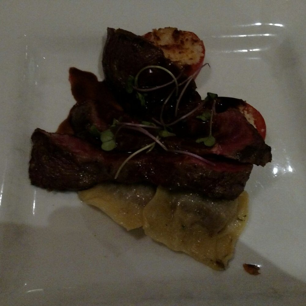 West Coast Grill - Wagyu Beef - Seared flank, grilled tomamto, cheek and froie gras ravioli, barbera rosemary reduction - American Near Me - Sooke, British Columbia West Coast Grill - Wagyu Beef - Seared flank, grilled tomamto, cheek and froie gras ravioli, barbera rosemary reduction - American Near Me - Sooke, British Columbia