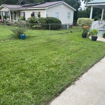 Sam Lawncare - a lawn with a fence and a house in the background - Lawn Services Near Me