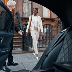 Automotive Luxury Limo and Car Service - A professional chauffeur holding open the door of a luxury limousine, representing reliable airport transportation services i...