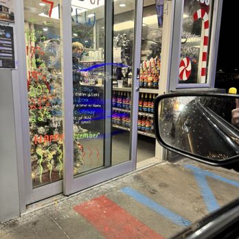 7 Brew Coffee - A small store entrance with glass doors features handwritten holiday messages and decorations, including a Christmas tree and candy cane window decals. - Coffee & Tea Near Me - Brownsburg, Indiana