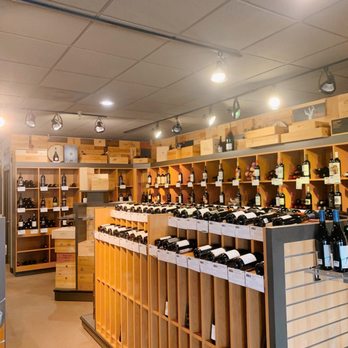 A Bottle or Two - $20+ selections - A wine shop features wooden shelving units filled with bottles of wine, illuminated by ceiling spotlights. - Beer, Wine & Spirits Near Me - Cincinnati, Ohio