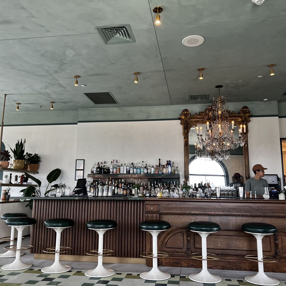 Bar Genevieve - a bar with stools and a chandelier - Mediterranean Near Me - Louisville, Kentucky