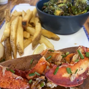 Slapfish - Lobster Roll - A lobster tail garnished with chopped chives, served with French fries and a bowl of Brussels sprouts on a wooden table. - Seafood Near Me - Albuquerque, New Mexico