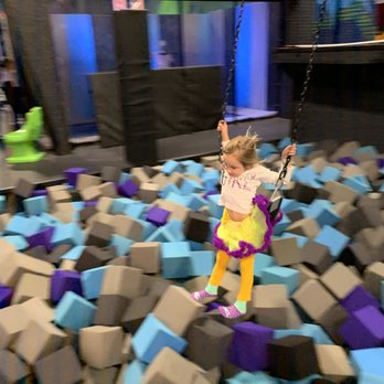 Sky Zone Trampoline Park - Birthday girl on kids swing over and drop into foam block mosh pit - Recreation Centers Near Me - Commerce Charter TWP, Michigan