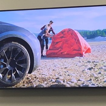Tesla Motors - Commercial in Tesla service waiting room showing a Tesla with the same 20 inch "Uberturbine" wheels off-roading - Auto Repair Near Me - Matthews, North Carolina