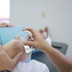 Catalyst Physical Therapy - Dr. Jennifer Hauskey using a scraping tool to promote blood flow and reduce inflammation.