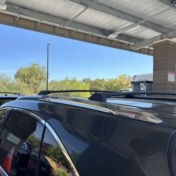 Costco - A black vehicle is parked outdoors under a metal overhang, with trees and a clear blue sky in the background. - Gas Stations Near Me - Ukiah, California