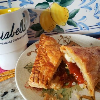 Guava Tree Cafe - Pastelillos de guayaba - A plate holds a slice of savory pastry with filling, placed on a decorative plate, next to a coffee mug with text, on a kitchen countertop. - Latin American Near Me - Albuquerque, New Mexico