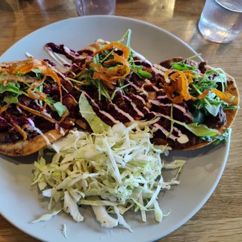 WeldWerks Brewing - Black bean and Chorizo tostadas - Three beef tostadas with greens, shredded carrots, and drizzled sauces are served on a white plate, accompanied by shredded cabbage. - Breweries Near Me - Greeley, Colorado