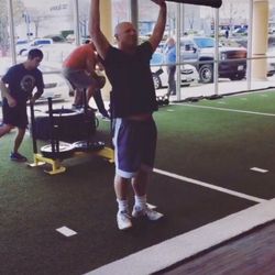 Ancrd Health & Fitness - A client working on strength and stability with a slush pipe on the turf side of the gym.