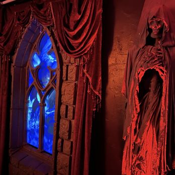 SpookEasy Lounge - a skeleton dressed in a robe and cloak in front of a stained glass window - Tea Rooms Near Me - Tampa, Florida
