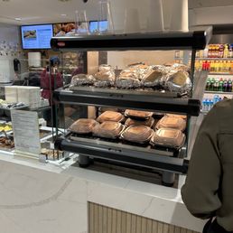 a man standing in front of a counter with a variety of baked goods a man standing in front of a counter with a variety of baked goods