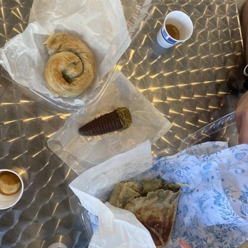 Yafa Bakery & Cafe - a woman sitting at a table with pastries and coffee - Bakeries Near Me - Somerville, Massachusetts