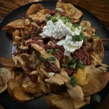 Murphy's Restaurant - A plate of nachos topped with shredded beef, melted cheese, sour cream, and chopped green onions, served on a black dish. - Seafood Near Me - Prescott, Arizona