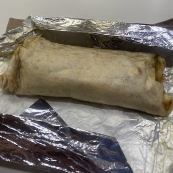 Barbacoa El Primo - Breakfast #2 - A burrito wrapped in a flour tortilla is placed on aluminum foil, with some of the foil peeled back, revealing the wrapped food. - Mexican Near Me - Albuquerque, New Mexico