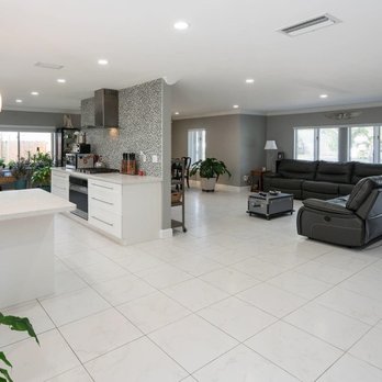 Unique Construction - Contemporary, open layout kitchen remodel with white cabinetry & quartz; highlighted by a mosaic glass tile accent wall & sleek range hood. - General Contractors Near Me - Miami, Florida