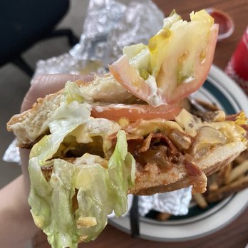 Five Guys - a person holding a sandwich with lettuce and tomato - Burgers Near Me - Surrey, British Columbia