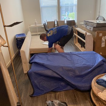 B&T Moving Company - Worker carefully dismantling sofa before covering with protective blanket. - Movers Near Me - Odessa, Florida B&T Moving Company - Worker carefully dismantling sofa before covering with protective blanket. - Movers Near Me - Odessa, Florida