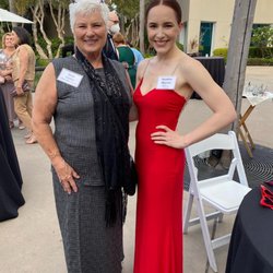 Milano Tailors - Two white women in formal wear, a gray dress on the left and a red dress on the right, at an awards show.