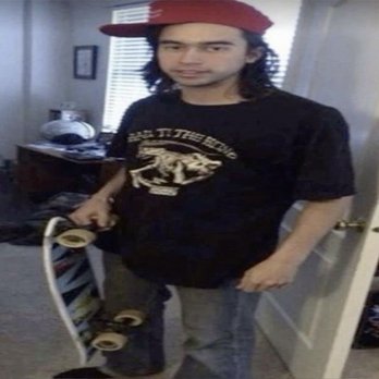 Applebee's Grill + Bar - A young man with long hair and a red cap stands indoors, holding a skateboard, with a room featuring a desk, window, and bookshelf in the background. - American Near Me - Gallup, New Mexico