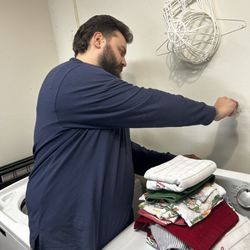 Certified-Environmental - Simon performing a moisture test behind a washing machine/dryer.