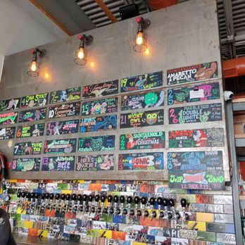 Tin Man - a woman standing in front of a wall of skateboards - Beer Bar Near Me - El Paso, Texas