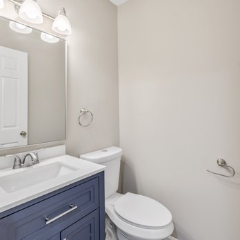The Vift Group - a bathroom with a toilet, sink, and mirror - General Contractors Near Me