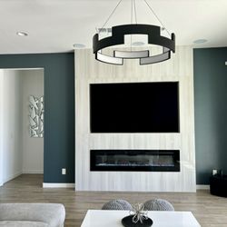 Apex Remodelations - TV Fireplace Wall and hung chandelier completed by Jose, and I painted my walls, midnight blue, to give that accent modern look!
