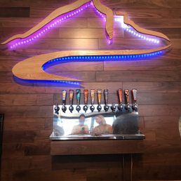 a beer tap with a neon sign above it
