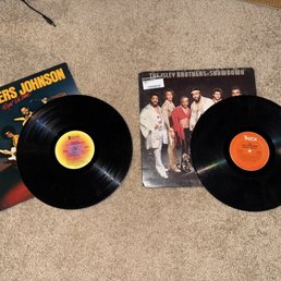 Brothers Johnson cover with a Rufus and Chaka Khan record.  Isley Brothers "Showdown" cover with their "Winner Takes All" record. - Two vinyl records are shown alongside their album covers, one featuring The Brothers Johnson and the other The Isley Brothers, in a retail store setting.