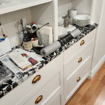 Ionion Marble - a kitchen with white cabinets and black countertops - General Contractors Near Me - Astoria, New York