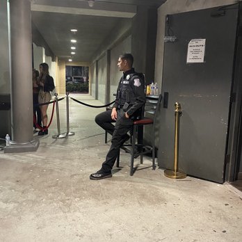 In Cahoots - a security officer sitting on a chair - Dance Clubs Near Me - Fullerton, California