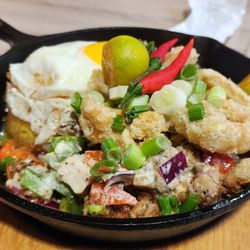Grill City - Pork Sisig Overload - Crispy pork bites with calamari and serrano chili. Served with Java rice and egg. The plate is HOT and sizzling!