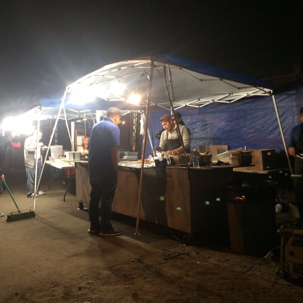 Tacos El Gordito Jr - a group of people standing under a tent - Street Vendors Near Me - Cudahy, California