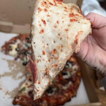 Indian Star Pizza - a hand holding a slice of pizza - Ice Cream & Frozen Yogurt Near Me - Suisun City, California