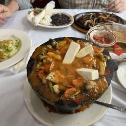 Picante's Canaan - Vegetarian molcajete front center, tostones to the left, fajitas with a side of rice and beans across the table, and chips and salsa