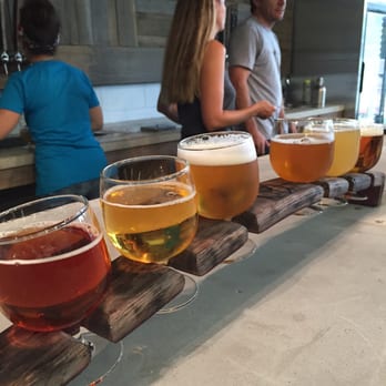 Commonwealth Brewing - Owners Jeremy & Natalie in background of a flights which run $15 - Breweries Near Me - Virginia Beach, Virginia Commonwealth Brewing - Owners Jeremy & Natalie in background of a flights which run $15 - Breweries Near Me - Virginia Beach, Virginia