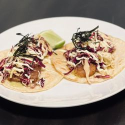 Uniyo Kitchen - SA-KA-NA White corn tortilla bedded with house special green sauce, layered with Japanese beer-battered fish, topped with house-pickled cab